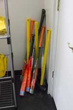 Photograph of metal bats, sledgehammers, and axes leaning upright against a corner at the house of purge